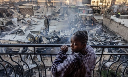 A woman looks from her balcony at the charred buildings