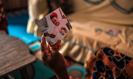 A woman’s hand holds a photograph of a young man