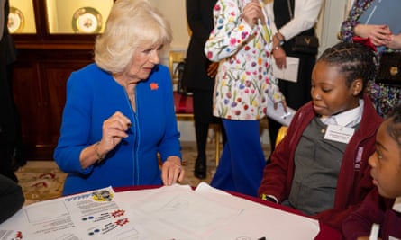 Camilla with schoolchildren sat at a table.