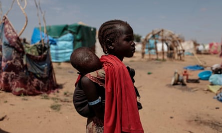 Gesma, 5, a Sudanese girl who fled the conflict in Geneina, carries her baby brother in Adre, Chad