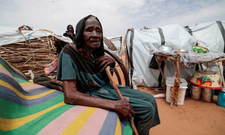 Halima Haroun Mohammed, 115, a Sudanese woman who fled the conflict in Geneina, sits outside her temporary shelter while holding  a walking stick