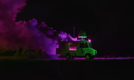 a truck moving a night with purple smoke behind it