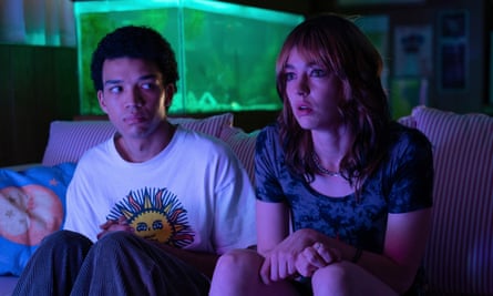 two young people sitting on a sofa with a glowing fish tank behind them