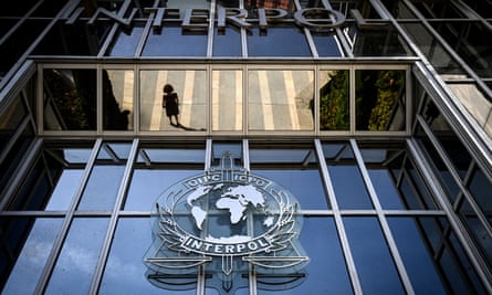 A woman reflected in the glass of the entrance of Interpol’s headquarters, featuring the Interpol logo