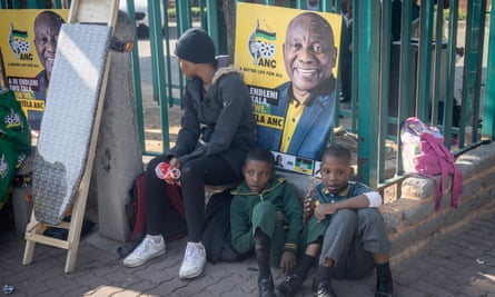 Children sit in front of an ANC campaign poster 