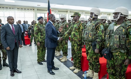 Kenyan flag, troops and men in suits including president shaking hands