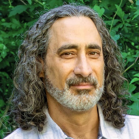 headshot of man with long hair and beard half-smiling