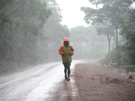 A man runs along an empty road in the rain