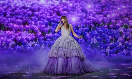 Taylor Swift in a large flowing dress in front of a purple back projection on stage in Lisbon during the Eras tour, 24 May 2024.