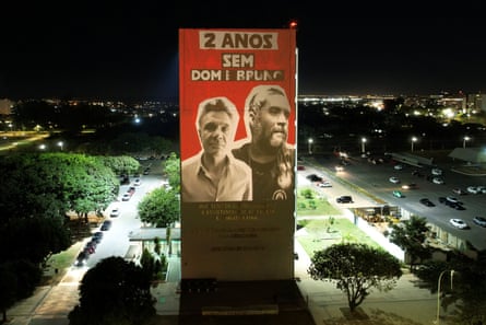 An image of two men on a high rise building in the middle of a busy road