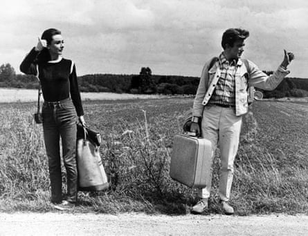 Audrey Hepburn and Albert Finney hitchhiking with suitcases by a rural road in a black-and-white image