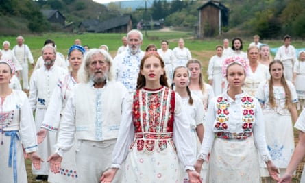 Cult members dressed in white, embroidered clothes stand in a field