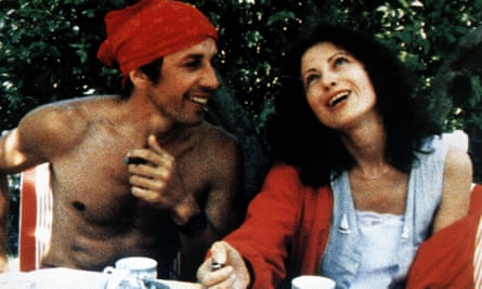 Marie Rivière with a male actor, sat at a. table outside beneath a tree