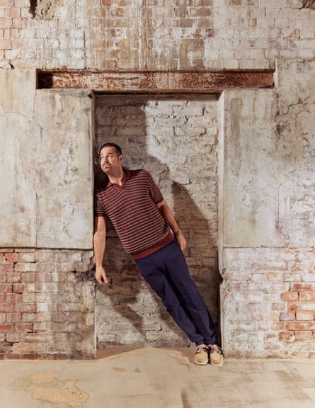 Danny Dyer, leaning against a weathered brick wall, wears red and yellow stripy polo shirt by Mr P (mrporter.com); trousers by waxlondon.com; and deck shoes by sebago.co.uk.