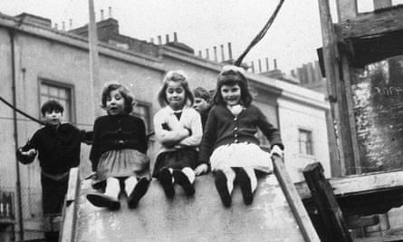 Three young girls sit on a slide in a black and white image from the documentary 7 Up series.