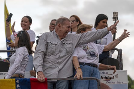 A man and woman smile and wave to the crowd at a rally