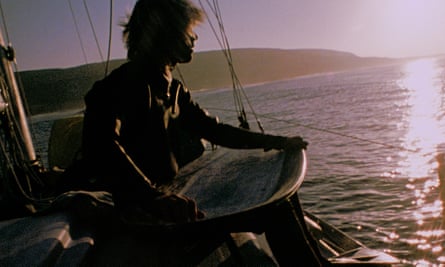 Greenough sitting on a yacht holding his surfboard