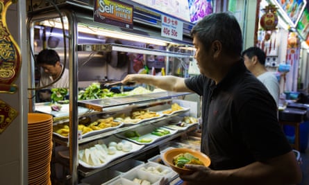 A customer picks food from a self-service stall at the Old Airport Road Food Centre in Singapore.