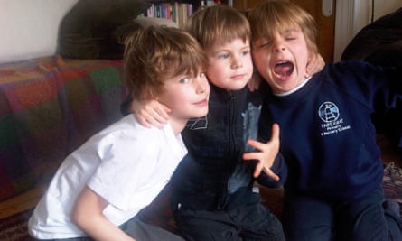 Three young boys hugging close.