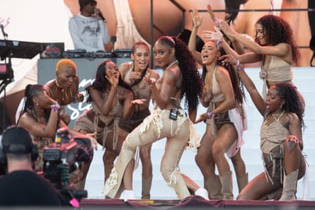 A young black African woman surrounded by black dancers performs on stage