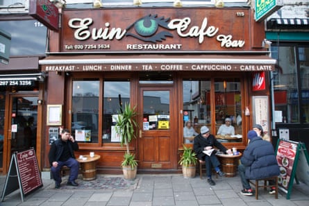 People sit outside Evin Cafe Bar next to two low barrel-style tables