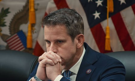 a man leans head on his hands in front of an american flag