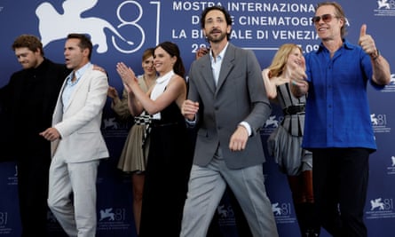 Cast members walk past a blue Venice film festival backdrop at a photocall