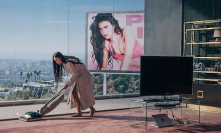 Moore in her latest film The Substance. She is pictured vacuuming in a penthouse flat overshadowed by a billboard featuring a glamorous image of a young woman