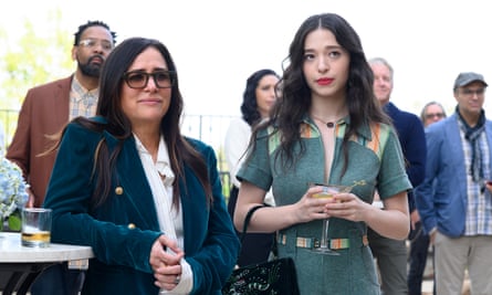 Pamela Adlon in sunglasses with a blue jacked and Mikey Madison in a zip up dress stand at a bar in the TV show Better Things