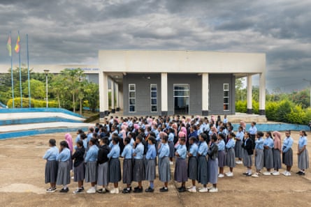 A crowd of girls in school uniform line up outside a school 