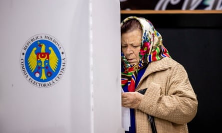 A woman looks at her ballot paper in a voting booth in Moldova