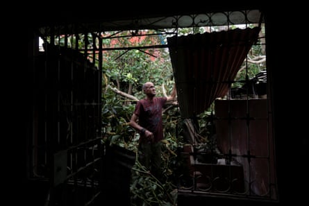 A man checks part of the destroyed roof of his home