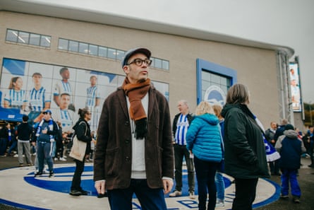 Alexis stands outside the stadium, in ordinary street clothes