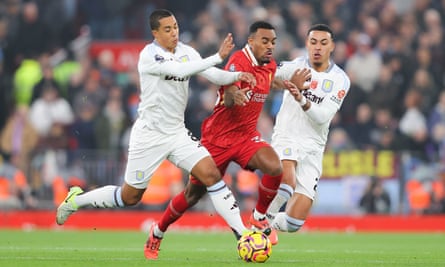 Ryan Gravenberch of Liverpool surges through the challenges of Aston Villa’s Youri Tielemans and Morgan Rogers.