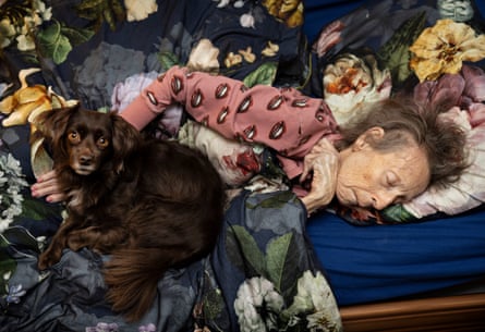 A woman lies in bed, apparently asleep, her hand on a pet dog