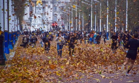 People walk along the Mall in central London in a blizzard of fallen leaves.