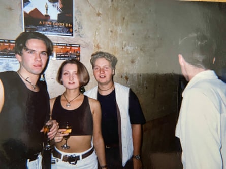 Neil (left), holding a drink, standing alongside a woman and a man