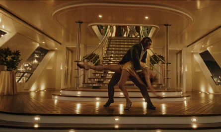 A still from the Robbie Williams biopic Better Man, showing the CGI monkey (playing Williams) dancing with a woman in front of a glitzy lit up staircase.