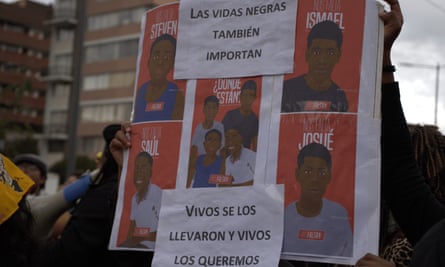 People hold up a placard with images of the four boys and their names – Steven, Ismael, Saul and Josué – plus, in Spanish, the phrases ‘black lives matter too’ and ‘they took them alive and we want them alive’