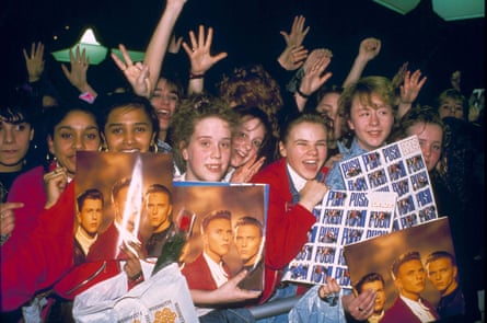 Girls in a crowd hold up pictures of Bros and copies of their LP Push.