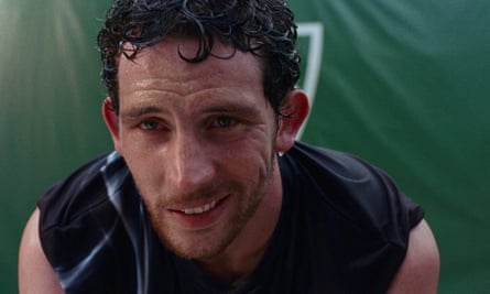 Man in tennis gear smirks, sweat dripping off his face and hair