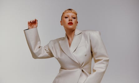 Portrait of Self Esteem in pale gold suit with one arm raised as if she is dancing