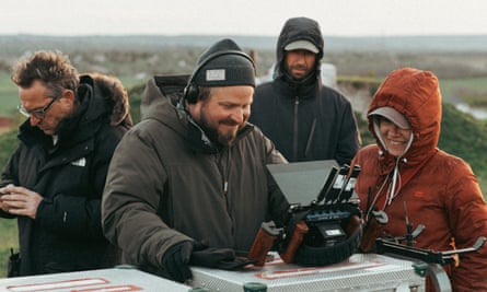 Brady Corbet in headphones looking at a screen, surrounded by others