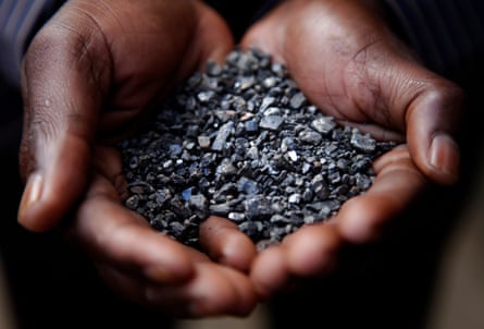 Cupped hands holding small shiny black stones.