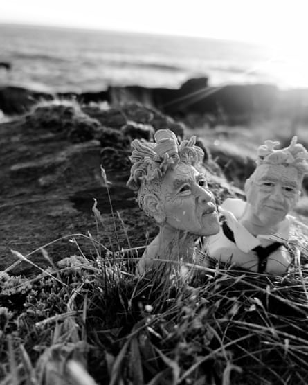 Two figurines of David Lynch on a beach.