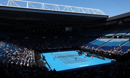 Members of the public watch Novak Djokovic (on serve) and Jack Draper practising at Rod Laver Arena