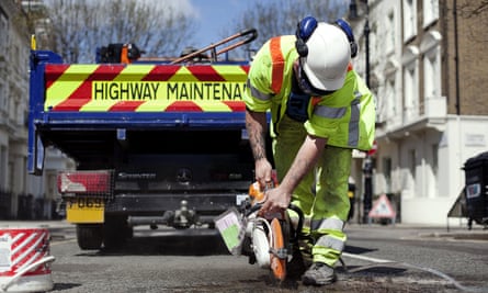 A Highway Maintenance worker fills in a pothole