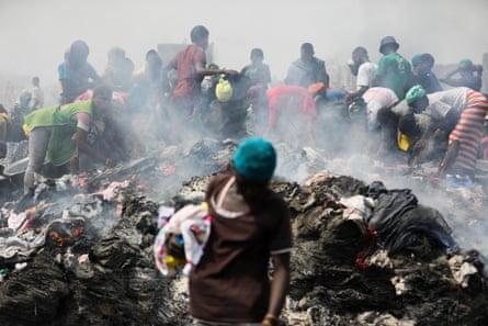 People scramble among the still smouldering remains to salvage what they can from the fire-devastated Kantamanto secondhand clothes market.