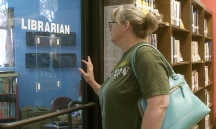 woman in a library looks through glass window marked ‘librarian’