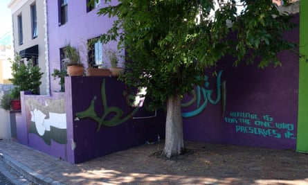 A purple house with a mural of a peace dove in front of a black and white flag, and wording stating: 'Heritage is for the one who preserves it'